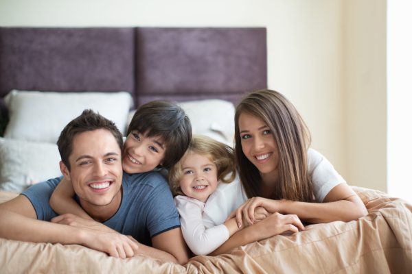 Happy family relaxing on a comfortable hotel bed